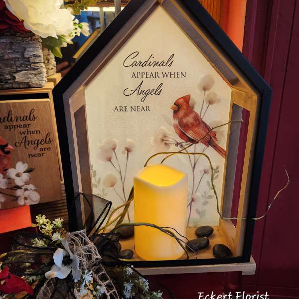 House-shaped memorial lantern with a lit candle and cardinal artwork