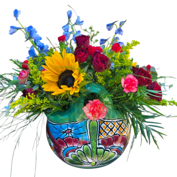 Mixed bouquet with a sunflower, red roses, blue delphinium, and pink carnations in a painted vase.