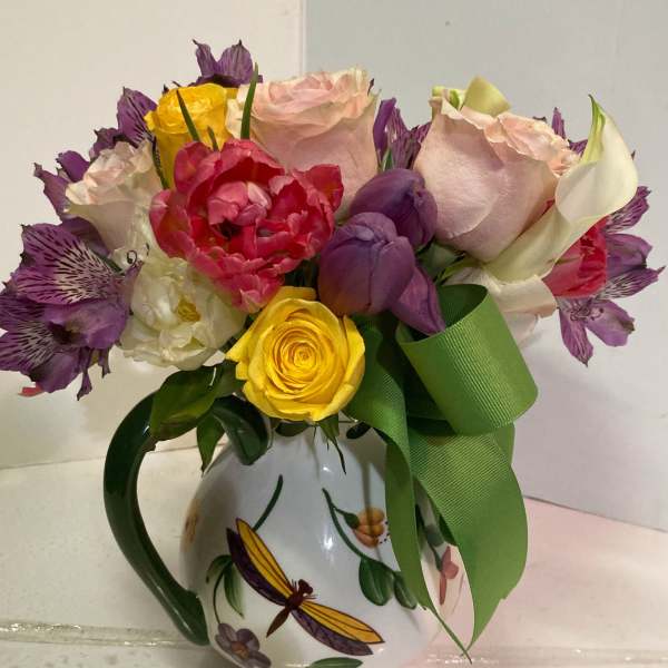 Bouquet of mixed roses and tulips in a decorative mug vase