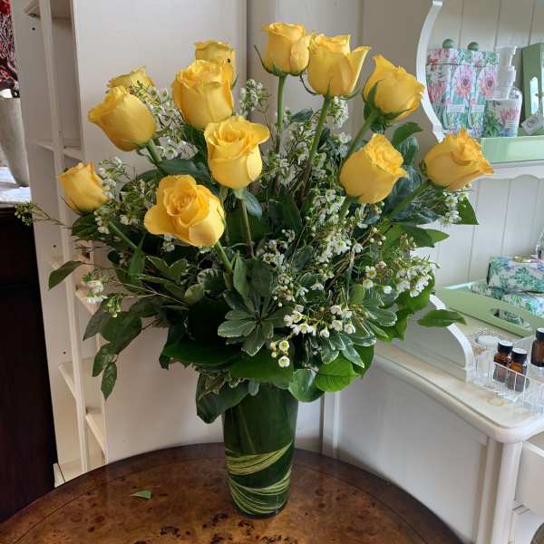 Yellow roses arranged in a tall green glass vase