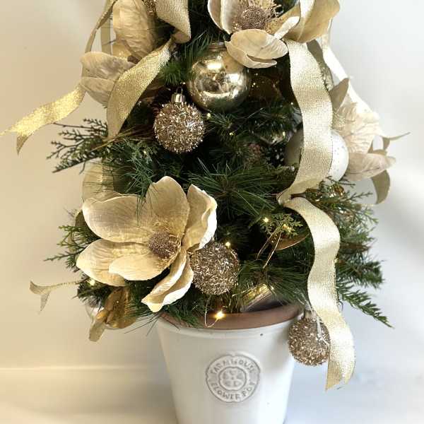 Mini Christmas tree with gold flowers, ribbon, and ornaments in a white pot