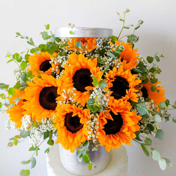 Bouquet of sunflowers and white filler flowers in a silver vase