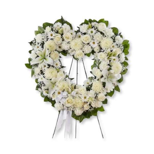 Heart-shaped white floral wreath on a stand with ribbon