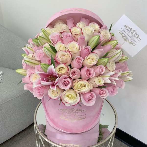 Pink and cream roses with lilies arranged in a pink hat box
