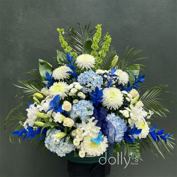 Large blue and white floral arrangement in a dark container