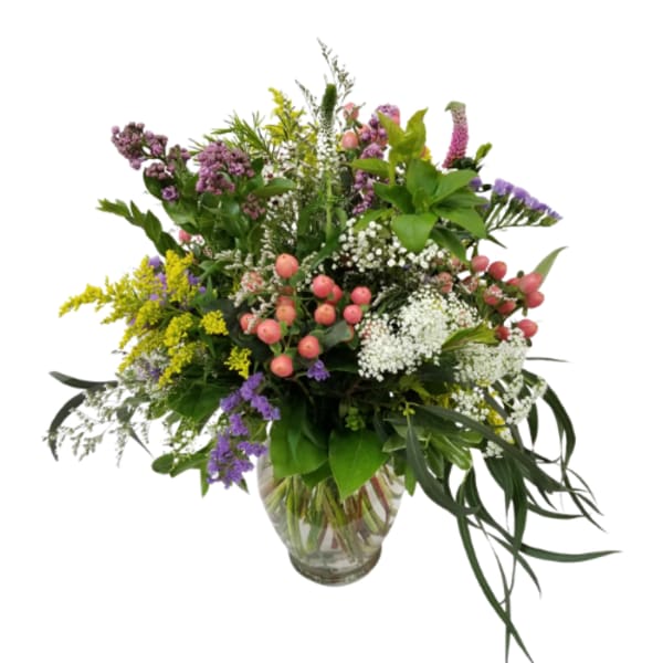 Mixed bouquet of purple, white, pink, and yellow flowers in a glass vase