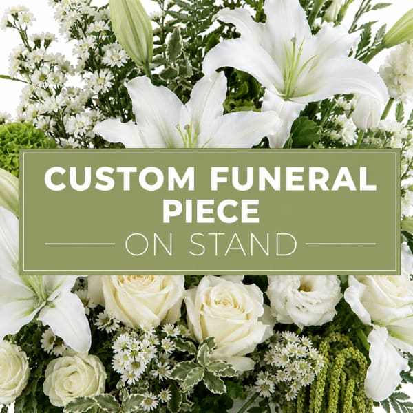 White lilies and roses arranged around a funeral sign on a stand