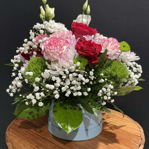 Mixed bouquet of red and pink roses with white filler flowers in a round box