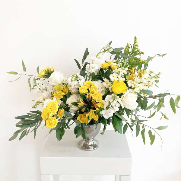 Yellow and white floral arrangement in a silver vase