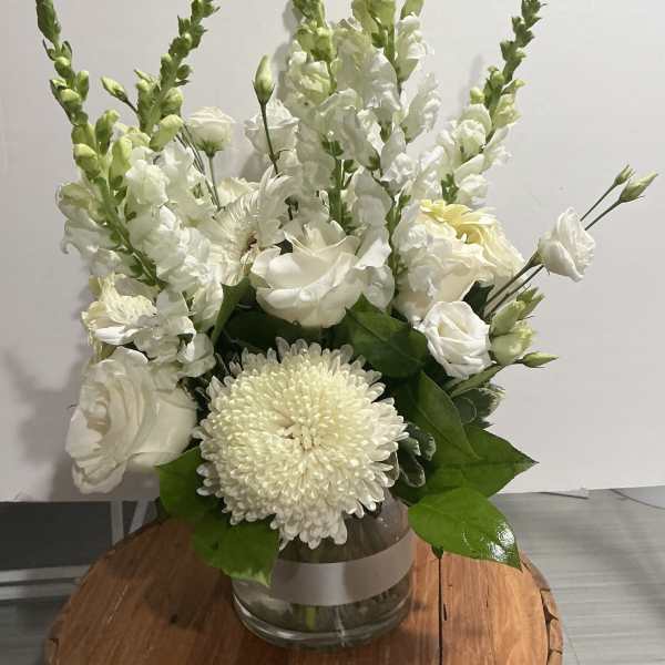 White floral arrangement in a glass vase with tall snapdragons and chrysanthemums