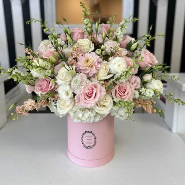 Pink and white roses arranged in a pink hat box