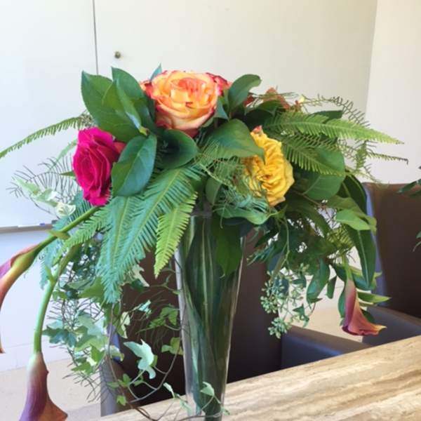 Mixed roses and calla lilies in a tall glass vase