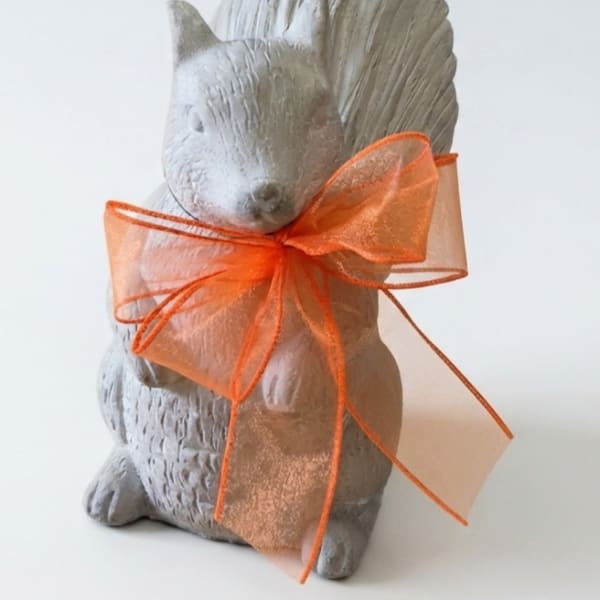 Gray squirrel figurine tied with an orange sheer ribbon