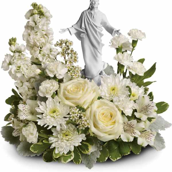 White floral arrangement with a small statue of Jesus in the center