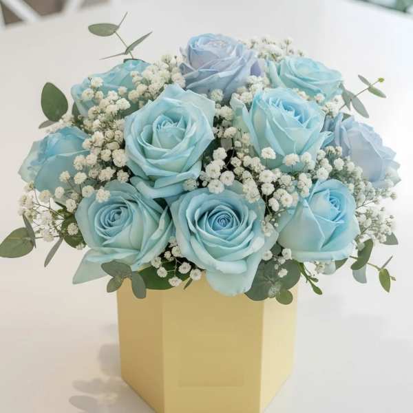 Blue roses arranged in a yellow box with baby's breath