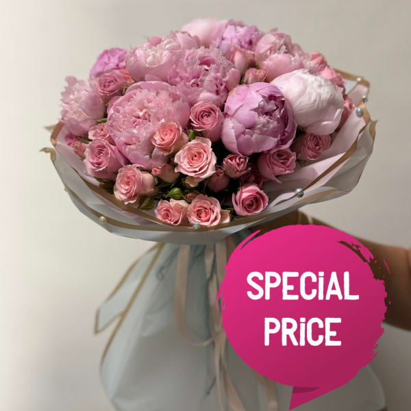 Pink bouquet of peonies and roses wrapped in pale paper