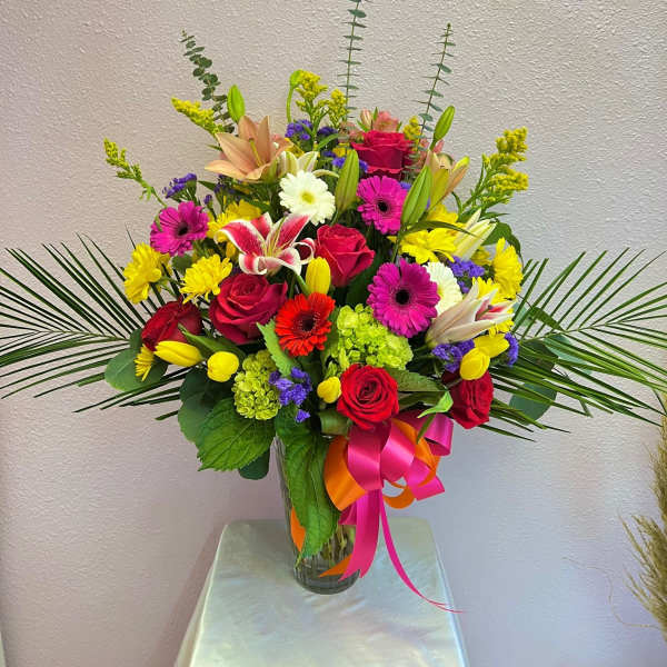 Colorful mixed bouquet in a clear glass vase with ribbon