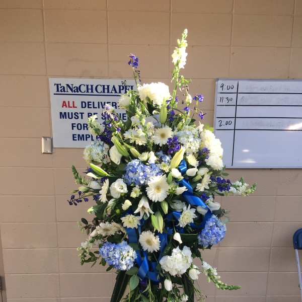 Tall standing floral spray with white and blue flowers on a tripod easel