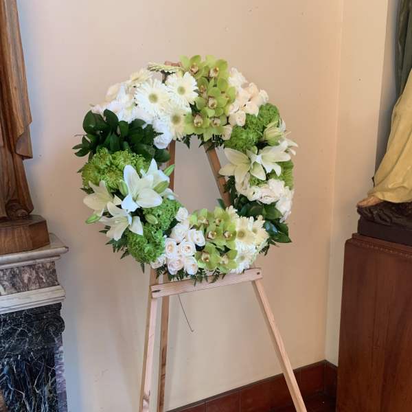 White and green floral wreath on a wooden easel