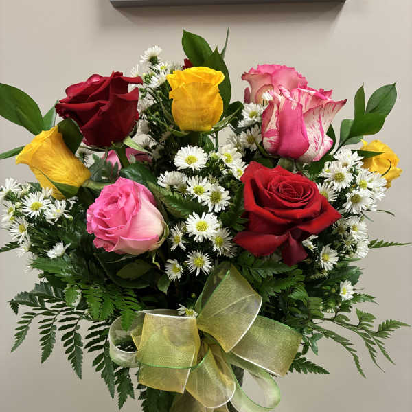Bouquet of multicolored roses and white daisies in a glass vase