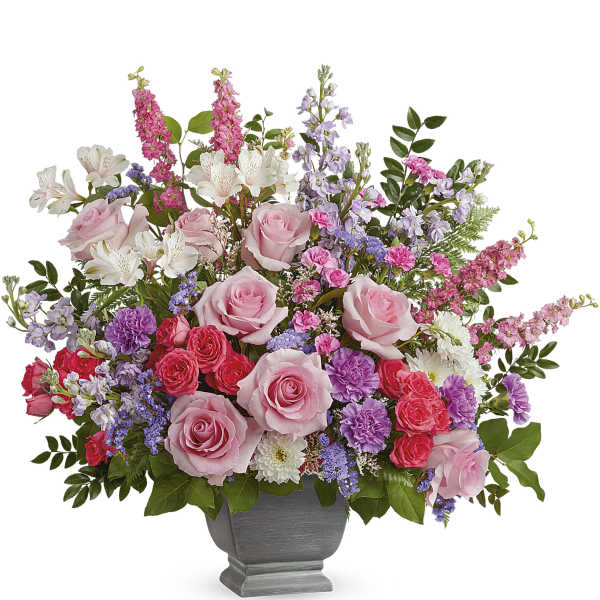 Mixed pink and purple flower arrangement in a gray pedestal vase