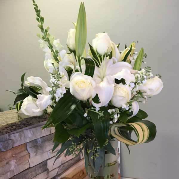 White roses and lilies arranged in a clear glass vase.