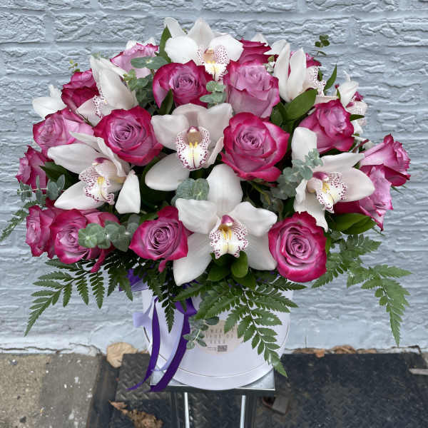 Pink roses and white orchids arranged in a white hat box