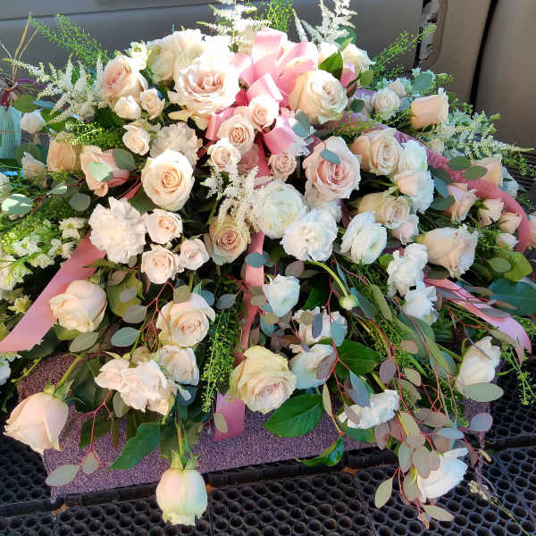 Large arrangement of pale pink and white roses with ribbon accents