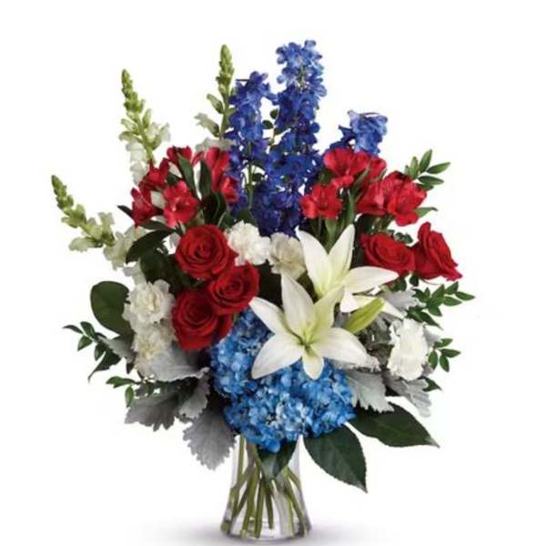 Bouquet of red roses, blue flowers, and white lilies in a clear vase