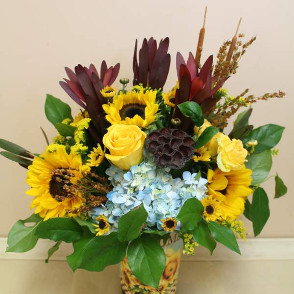 Sunflower and yellow rose arrangement in a printed cup vase