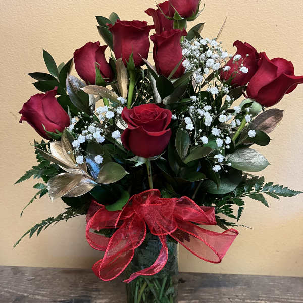 Red roses arranged in a clear glass vase with a red ribbon