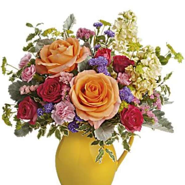 Bouquet of orange and red roses in a yellow pitcher vase