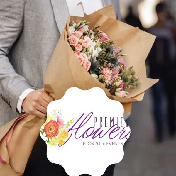 Handheld bouquet of pink and white flowers wrapped in brown paper