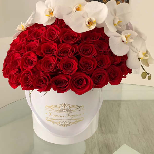Red roses with white orchids in a white hatbox