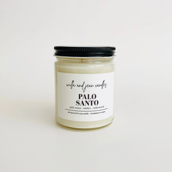 Jar candle with a black lid and pale wax on a white background