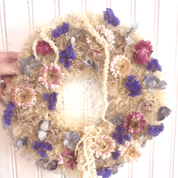 Dried floral wreath with purple and pink flowers on a straw base