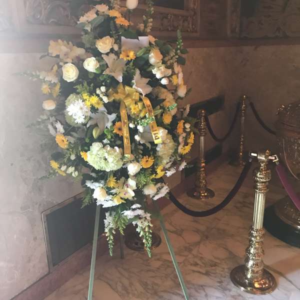Large funeral spray of white and yellow flowers on an easel
