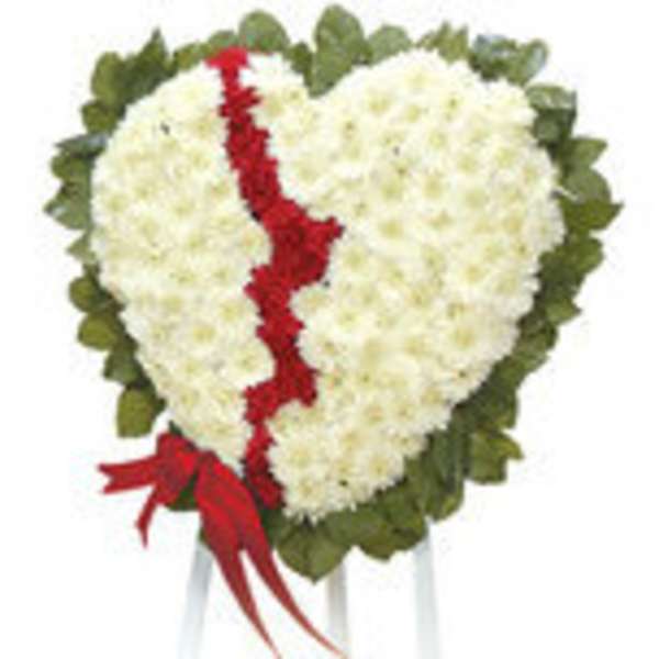 Heart-shaped white floral tribute with a red ribbon and green border