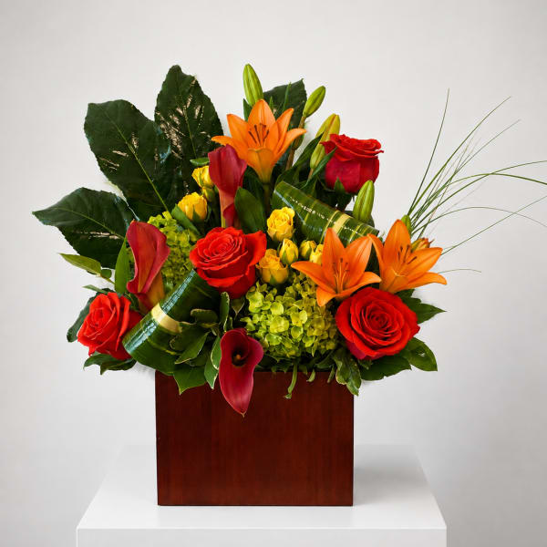 Tropical arrangement with red roses, orange lilies, and calla lilies in a wooden box