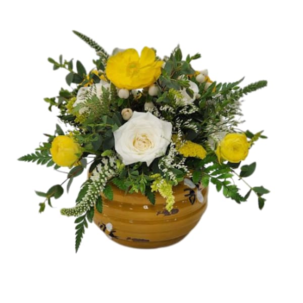 Yellow and white flowers arranged in a round ceramic vase