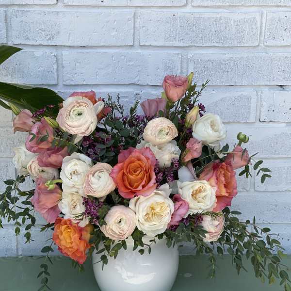 Mixed pink, white, and orange flowers in a white vase