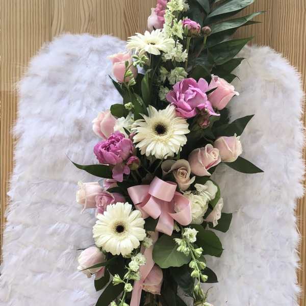 White angel wings with a pink and white floral spray on a stand