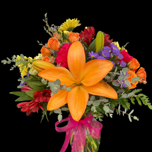 Colorful bouquet with orange lilies, roses, and purple flowers in a glass vase
