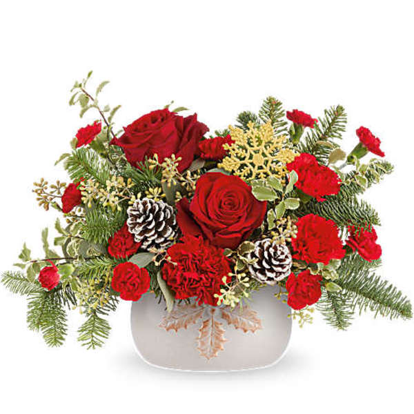 Red roses and carnations in a white vase with pinecones and evergreen accents