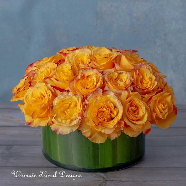 Yellow roses arranged in a low green glass vase