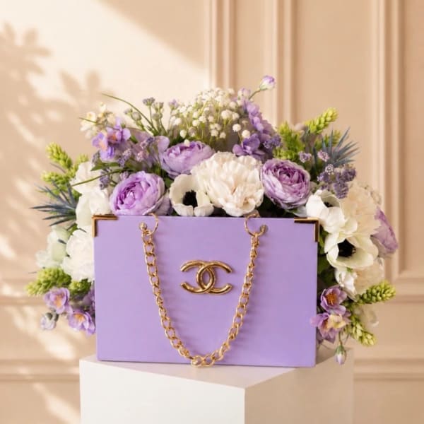 Lavender floral arrangement in a purple handbag-shaped box with a gold chain