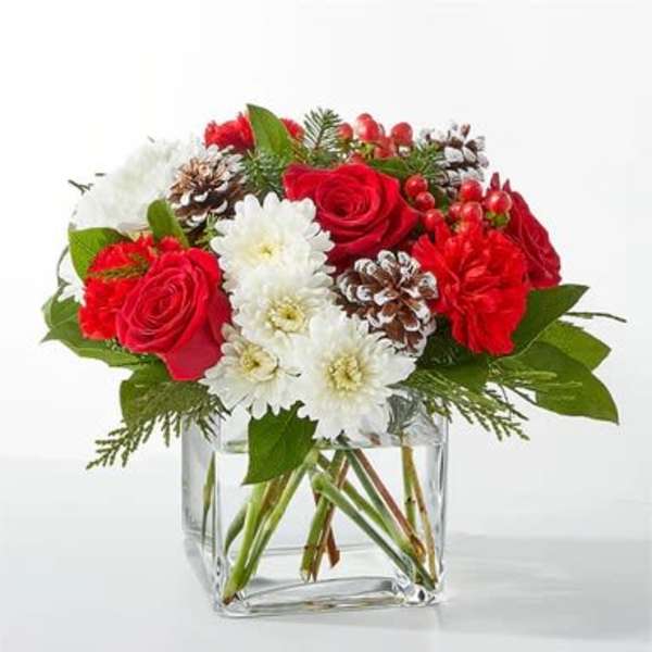 Red roses and white daisies in a clear glass vase with pinecones