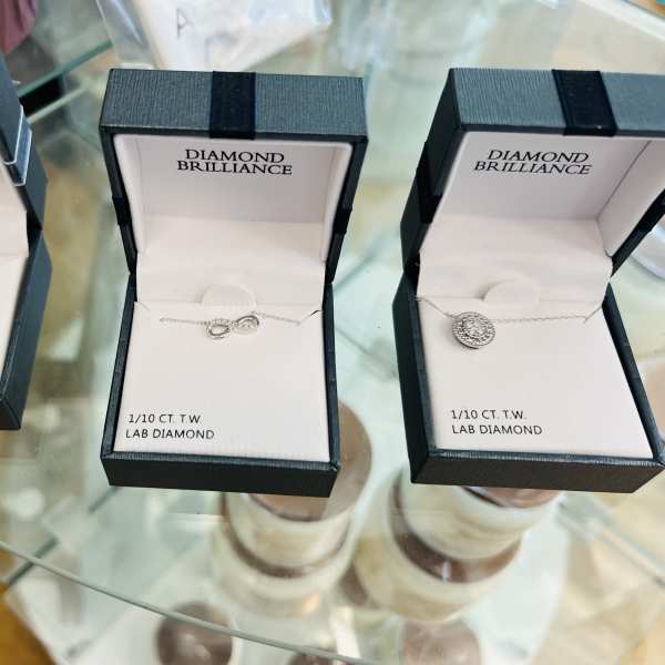 Three open jewelry boxes with necklaces on a glass table