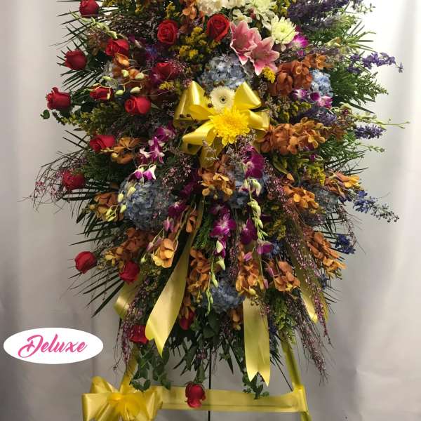Large standing spray with red roses, blue hydrangeas, and yellow ribbon