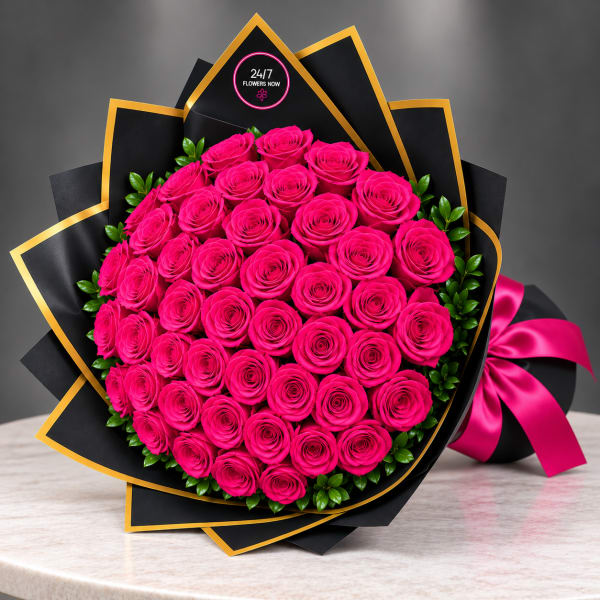 Large bouquet of hot pink roses wrapped in black paper with gold trim and a pink ribbon